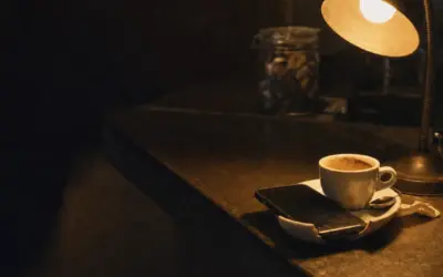 Uno smartphone appoggiato su un piattino accanto a una tazzina di caffè al bancone