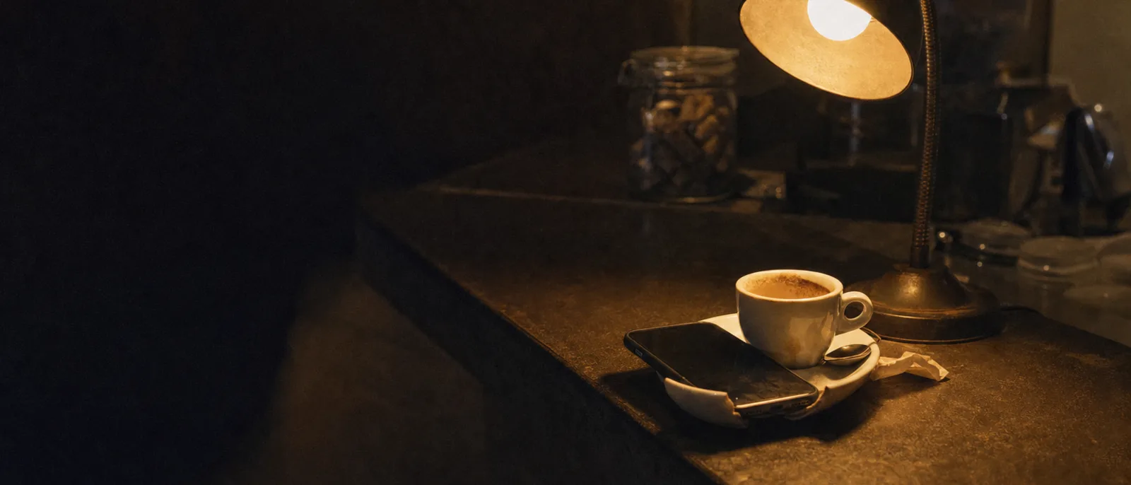 Uno smartphone appoggiato su un piattino accanto a una tazzina di caffè al bancone